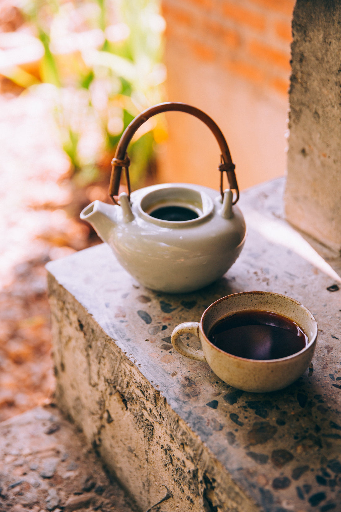 A ceramic kettle and cup of black coffee on a stone surface — perfect for exploring brewing methods